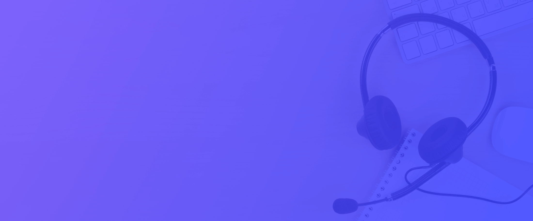 Headset with microphone resting on a desk alongside a keyboard, mouse, and notepad.