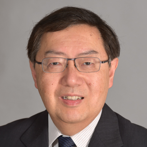 Portrait of an Asian man wearing glasses, a dark suit, white striped shirt, and a dark tie against a gray background.